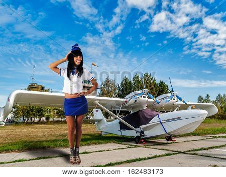 Attractive young stewardess smiles near small airplane