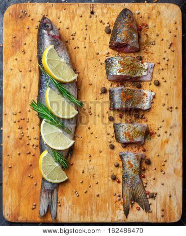 Whole And Cut Grey Mullet Fishes Lie On Light Wooden Cutting Board With Lemon Segments, Rosemary Bra