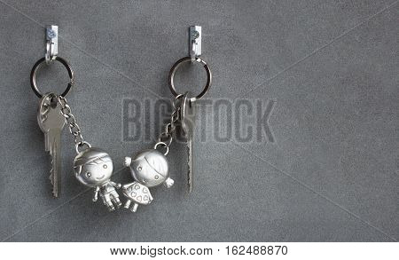 Keyrings boy and girl pulling hands. Lovers keychains love. Gray background