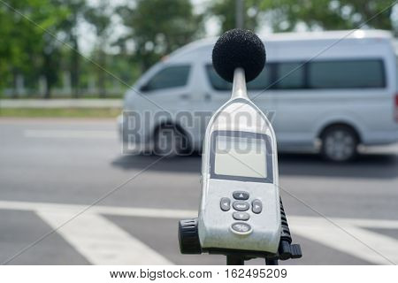 Measuring the noise of cars on the road with a sound level meter.