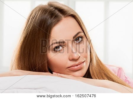 young woman laying in bedroom at early morning, on lightgray window background