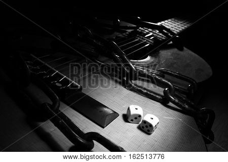 A black and white photo with film noir vibes of a pair of `snake eyes` watching you on a chained acoustic guitar.