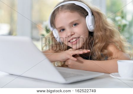 cute girl listening to music using headphones and laptop