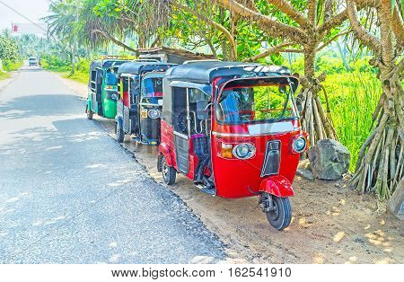 The line of colorful tuk tuks at the road in Peraliya Sri Lanka.