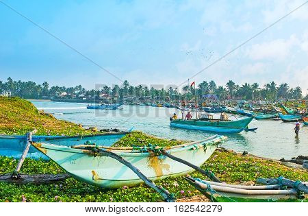 HIKKADUWA SRI LANKA - DECEMBER 5 2016: The fishing harbor is the noisy crowded place with old boats departing and arriving all day long on December 5 in Hikkaduwa.