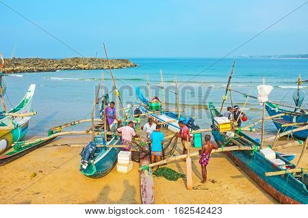 HIKKADUWA SRI LANKA - DECEMBER 5 2016: The fishermen unwind and fold the net to their boat at the fishing harbor on December 5 in Hikkaduwa.