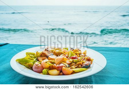 The tasty deviled fish with stewed vegetables on the restaurant's table at the ocean Hikkaduwa Sri Lanka.