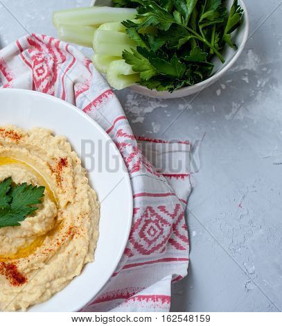 Home classic hummus with celery pitoy.Vid top on gray concrete background. Vegan Food Concept.