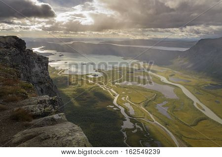 Cliff overlooking big river delta in lake autumn landscape with rain from clouds
