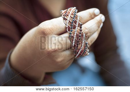 Girl wearing red top holding golden Bangle.