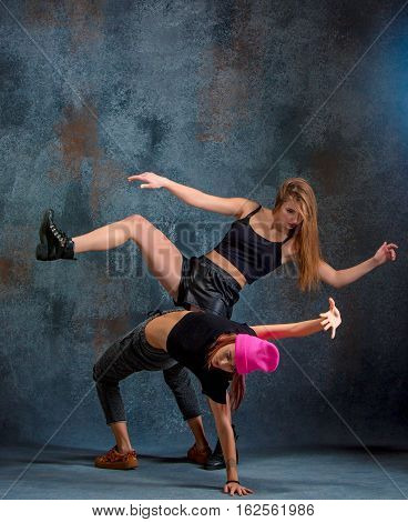 The two attractive girls dancing twerk iat the blue studio background