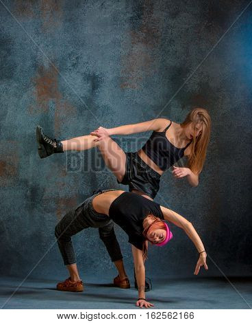 The two attractive girls dancing twerk iat the blue studio background
