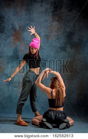 The two attractive girls dancing twerk iat the blue studio background