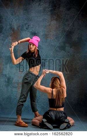 The two attractive girls dancing twerk iat the blue studio background