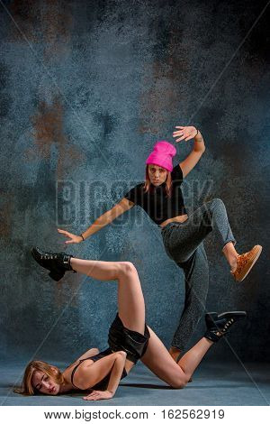 The two attractive girls dancing twerk iat the blue studio background