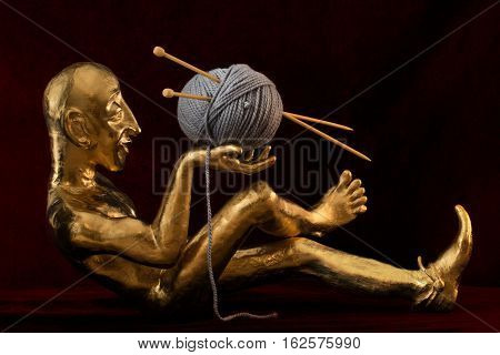 golden statuette with a ball of wool and knitting needles