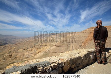 WADI MUJIB, JORDAN - MARCH 6, 2016 : A young Jordanian man looking at Wadi Mujib Canyon from Kings Road