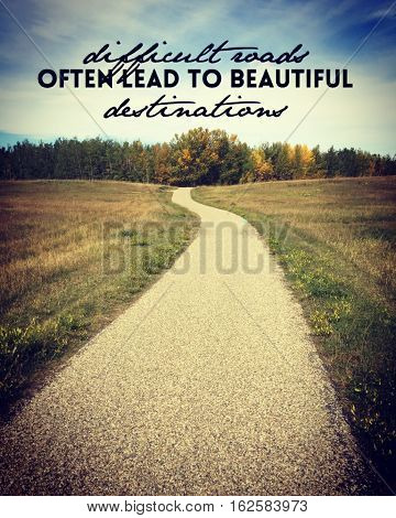 Inspirational quote on asphalt pathway road through grass field with colorful trees and sky in background.  Paved trail with slight bend leading into autumn trees. Autumn landscape.Instagram effects.