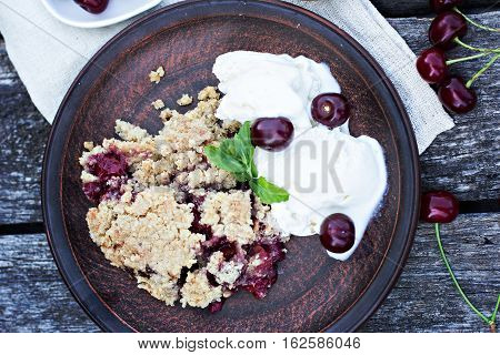 Homemade Cherry crumble wiht ice cream and cherries on an old wooden table background.Selective focus.