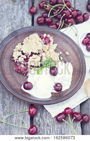 Homemade Cherry crumble wiht ice cream and cherries on an old wooden table background.Selective focus.