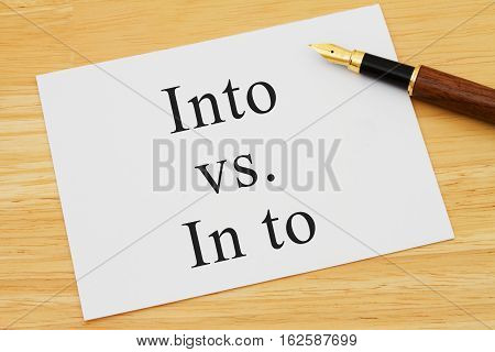 Learning to use proper grammar A white card on a desk with a pen with words Into vs In to