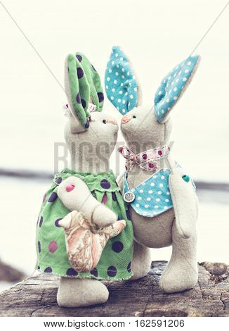 Two toy bunny in love on an old wooden surface. toned photo