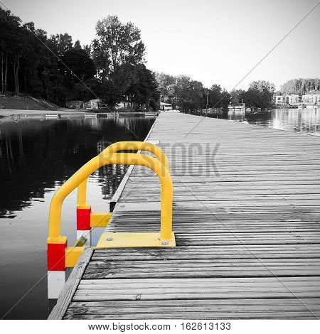 View of a wooden pier with ladder on the pond