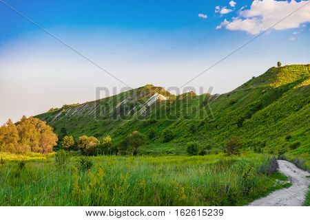 Green chalk hills under blue sky. The multilayered archaeological monument - Krapivinskaya settlement Belgorod region Russia. Summer landscape.