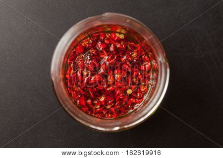 Red hot Trinidad moruga scorpion peppers chopped in olive oil on black background