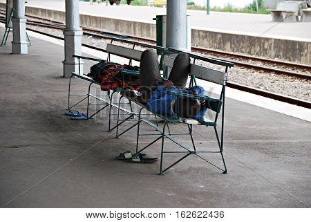 Two homeless men lying on a bench resting. Africa