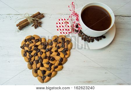 White plate in the form of seashells with coffee beans, cinnamon sticks and star anise, a festive tablecloth and cup with saucer on a dark wooden background.