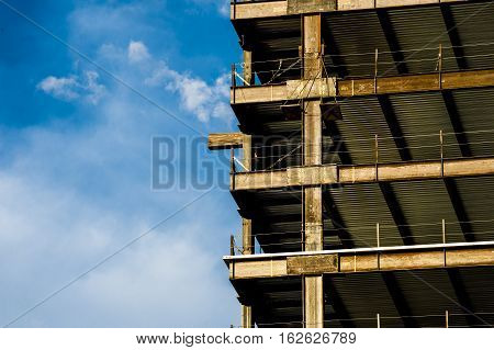high rise building under construction detail showing steel girders with blue sky and white clouds