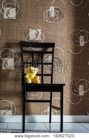 Yellow bear doll sitting on the chair, lonely yellow bear doll, single doll