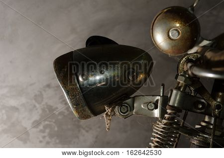 The old bike was parked cement wall left home. Rusty old lamp And bell on the handlebars.