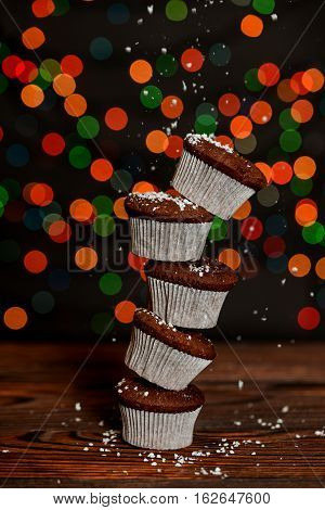Five chocolate cupcakes stacked to form a tower in the kitchen