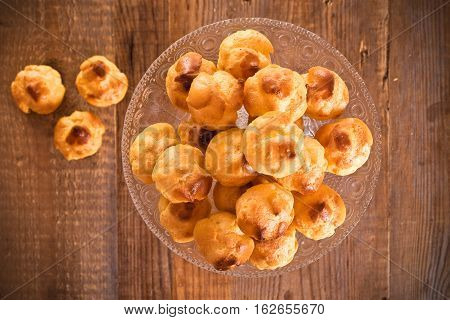 Group of sweet cream puffs on glass tray.