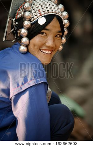 Mae Salong, Thailand - January 28, 2008 : 
In the mountains of northern Thailand. Portrait of a pretty young woman from the Akha ethnic group. To save her money Akha women sew silver coins on headdress.