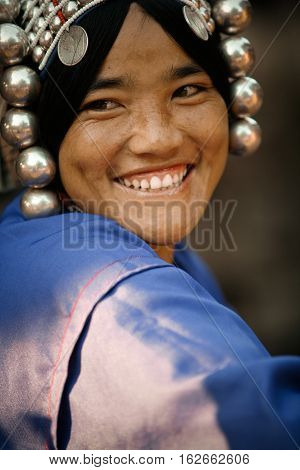 Mae Salong, Thailand - January 28, 2008 : 
In the mountains of northern Thailand. Portrait of a pretty young woman from the Akha ethnic group. To save her money Akha women sew silver coins on headdress.