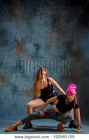 The two attractive girls dancing twerk iat the blue studio background