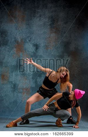 The two attractive girls dancing twerk iat the blue studio background