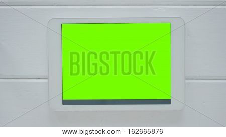 Horizontal tablet computer with green screen on white wooden background. Technology and internet concept