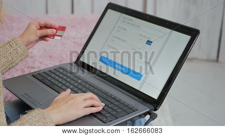 Young woman buying goods from the internet and entering number security code from credit card on laptop. Online, technology and internet concept.