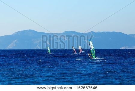 group of windsurfers on a background of mountains in the Aegean sea .