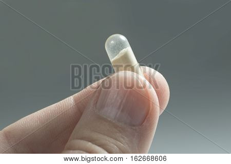Close up of probiotic capsule between the fingers