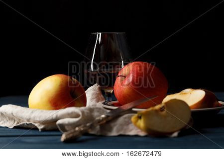 Glass With Calvados Brandy And Yellow Apples On A Wooden Table