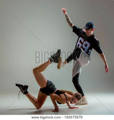 The two young girl and boy dancing hip hop at the gray studio background