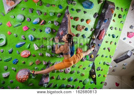 Young beautiful  woman climbing on an artificial wall