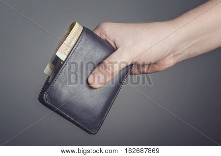 Leather wallet in hand isolated on dark background