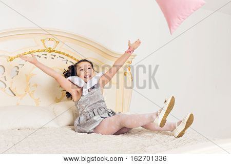 baby girl in her bed unwilling to sleep throws the pillows.