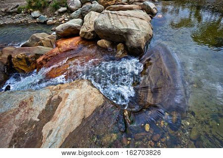 Small waterfall in crystal clear creek on rocks